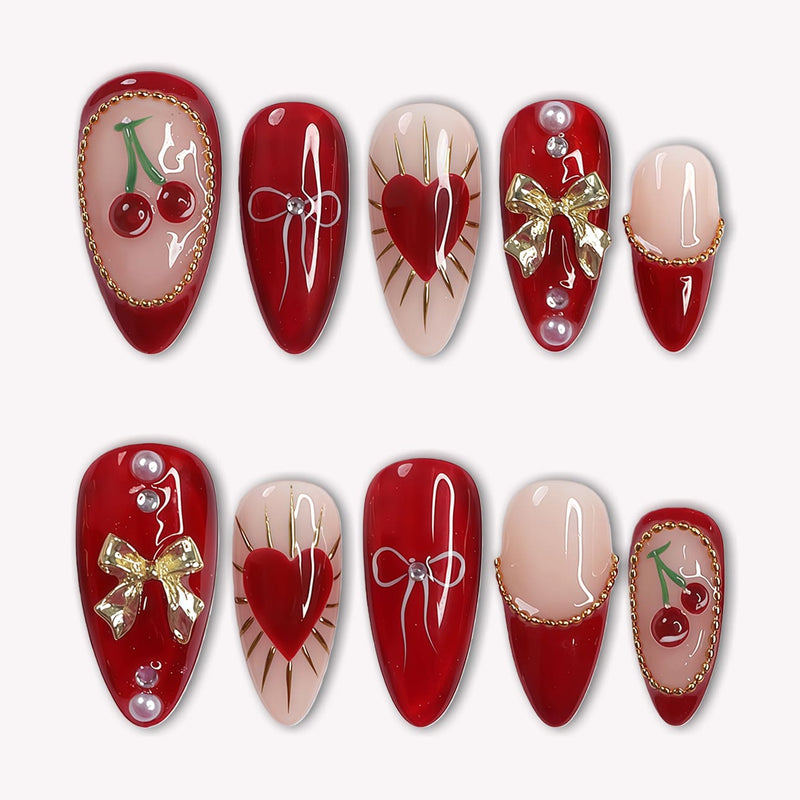Cherry Devotion press-on nail set in red, blush, and gold with cherries, bows, hearts, and pearl accents arranged on a white background