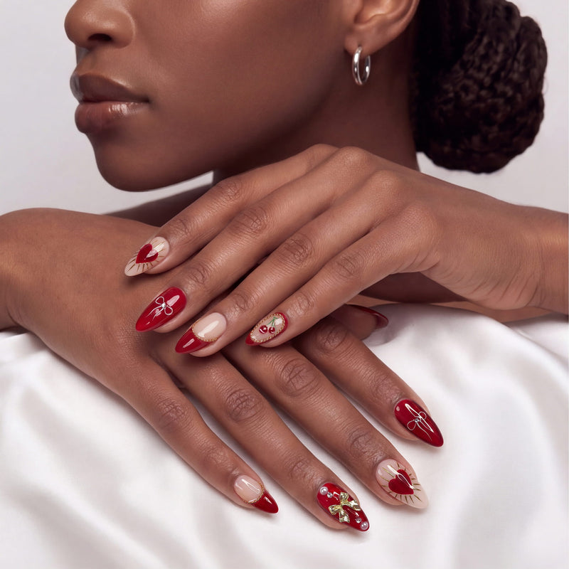 Lifestyle portrait of a hand model wearing Cherry Devotion press-on nails, with hands stacked and red, blush, and gold cherry details visible