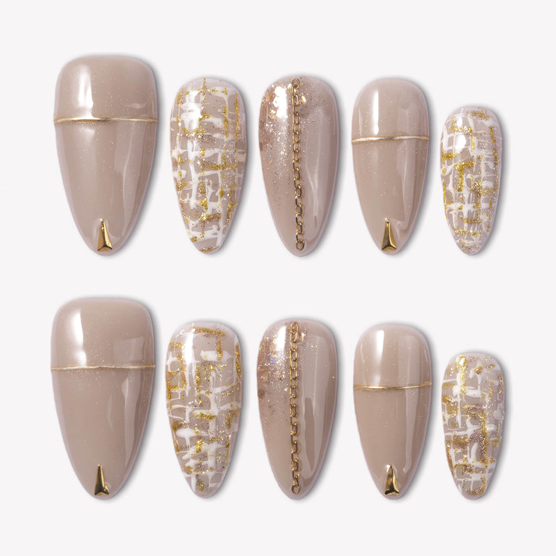 Flat lay of beige press-on nails with gold chain, gold tips, and tweed plaid accents