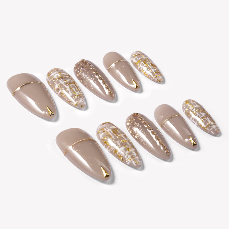 Flat lay of beige press-on nails with gold line accents, tweed plaid details, and glitter finish
