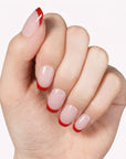 Classic Daily Set press-on nails worn on a hand with glossy pale pink nails and red French tips