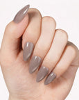 Classic Daily Set press-on nails worn in a close-up hand pose with glossy taupe almond-shaped nails