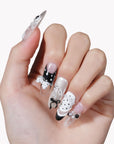 Hand model wearing Coco Dot Affair press-on nails with black and white polka dots, bows, lace, and pearl accents