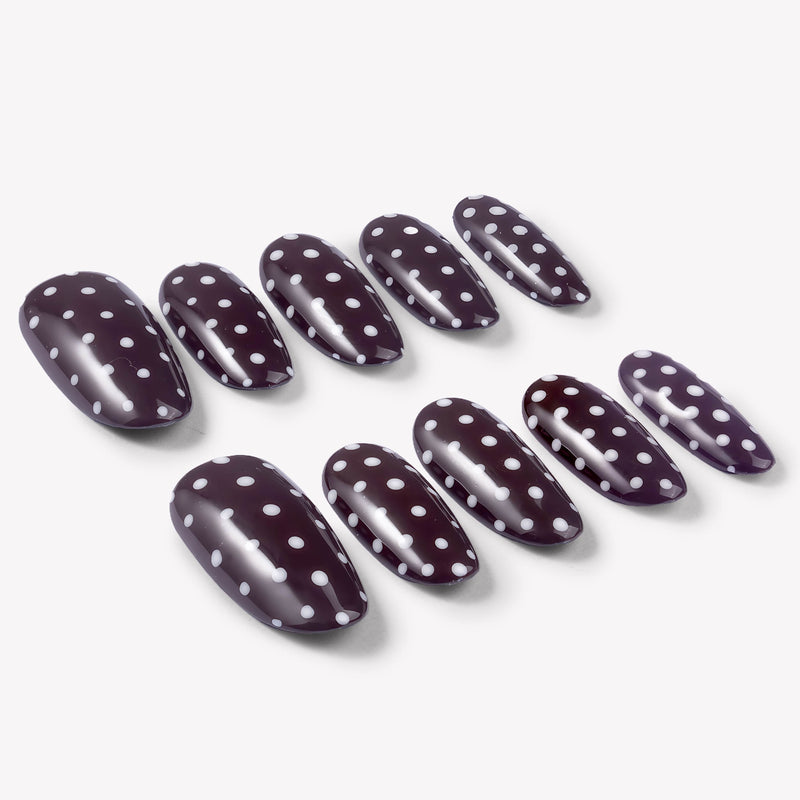 Angled flat lay of Cocoa Dots press-on nails with glossy dark brown bases and raised white polka dot designs