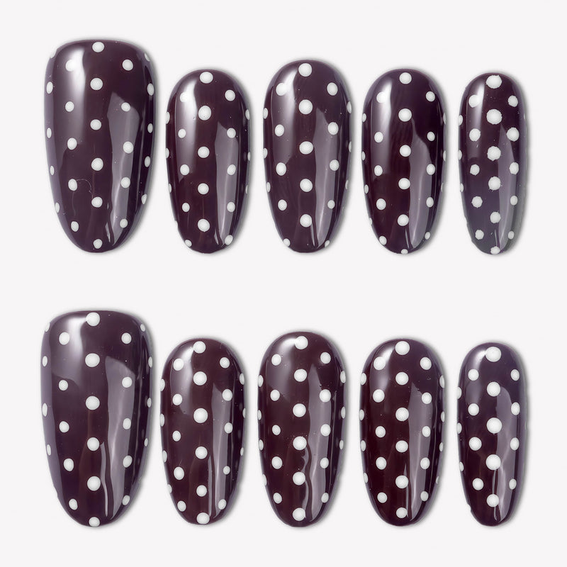 Cocoa Dots press-on nails with glossy dark brown bases and raised white polka dot designs arranged in a flat lay
