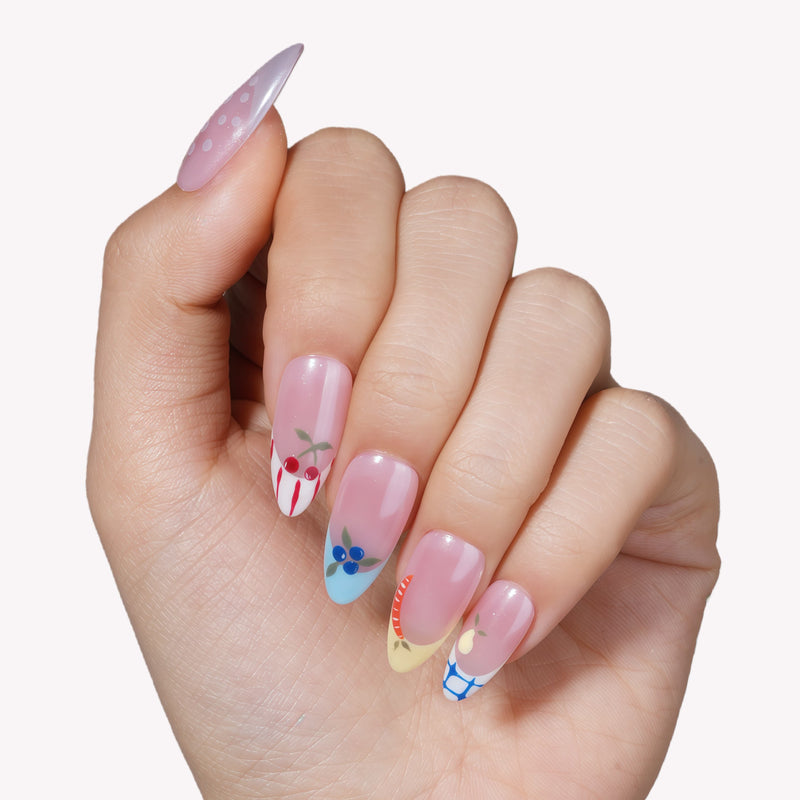 Hand model wearing Colorful Harvest press-on nails with pastel pink polish and fruit accent details