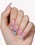 Hand model wearing Colorful Harvest press-on nails with pastel pink polish and fruit accent details
