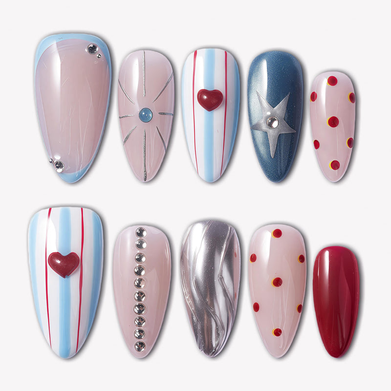 Cosmic Candy press-on nails with blue and white stripes, red heart charms, silver star accent, red polka dots, rhinestones, and glossy nude bases