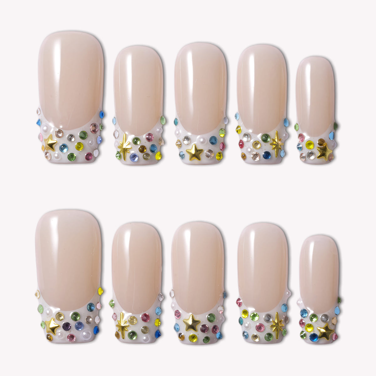 Flat lay of nude French tip press-on nails with multicolor rhinestones, pearls, and gold star charms on a white background