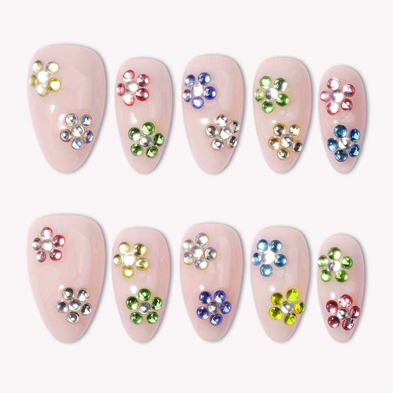 Crystal Dew handmade press on nails arranged in a white flat lay with colorful rhinestone flower accents