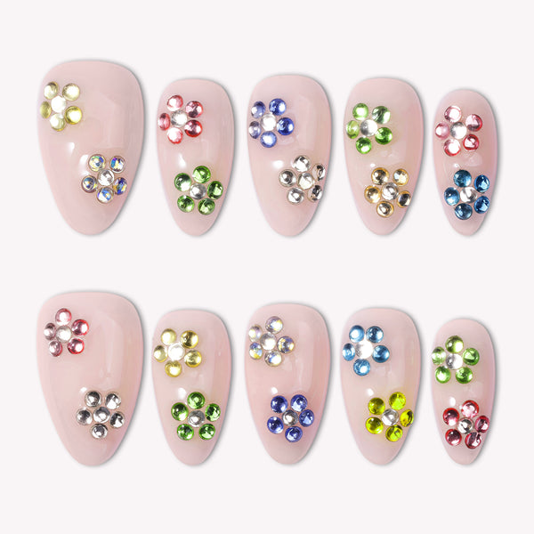 Crystal Dew handmade press on nails arranged in a white flat lay with colorful rhinestone flower accents