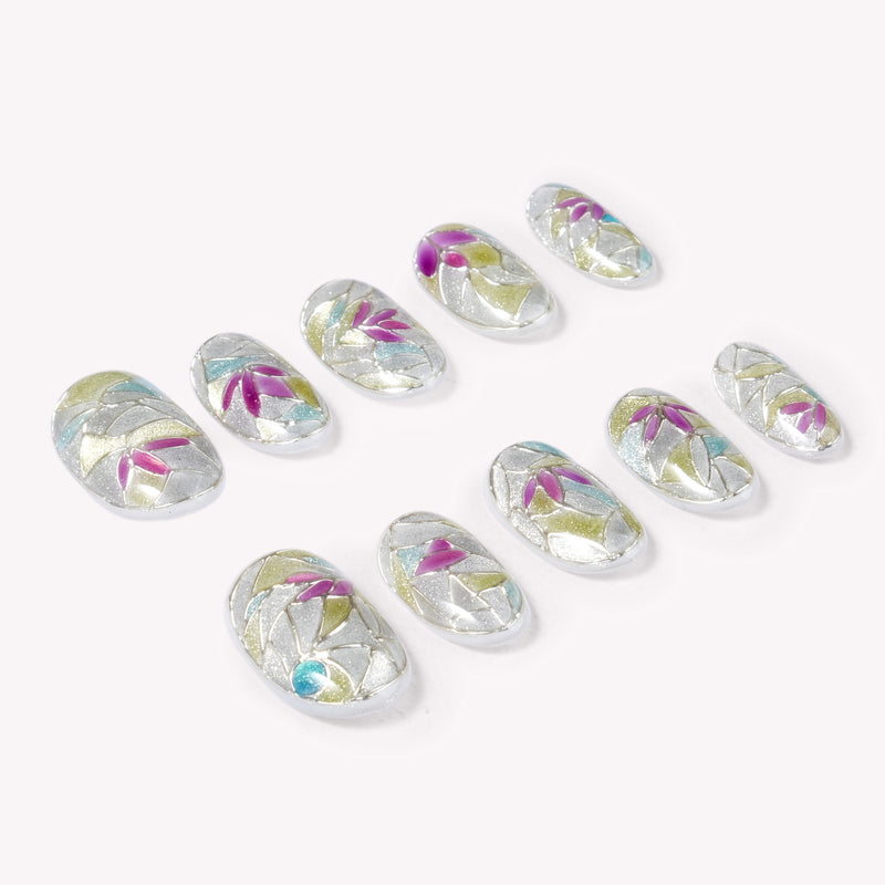 Angled flat lay of Crystal Leaves silver iridescent nails with pink, blue and green leaf accents