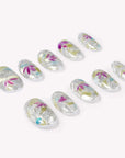 Angled flat lay of Crystal Leaves silver iridescent nails with pink, blue and green leaf accents