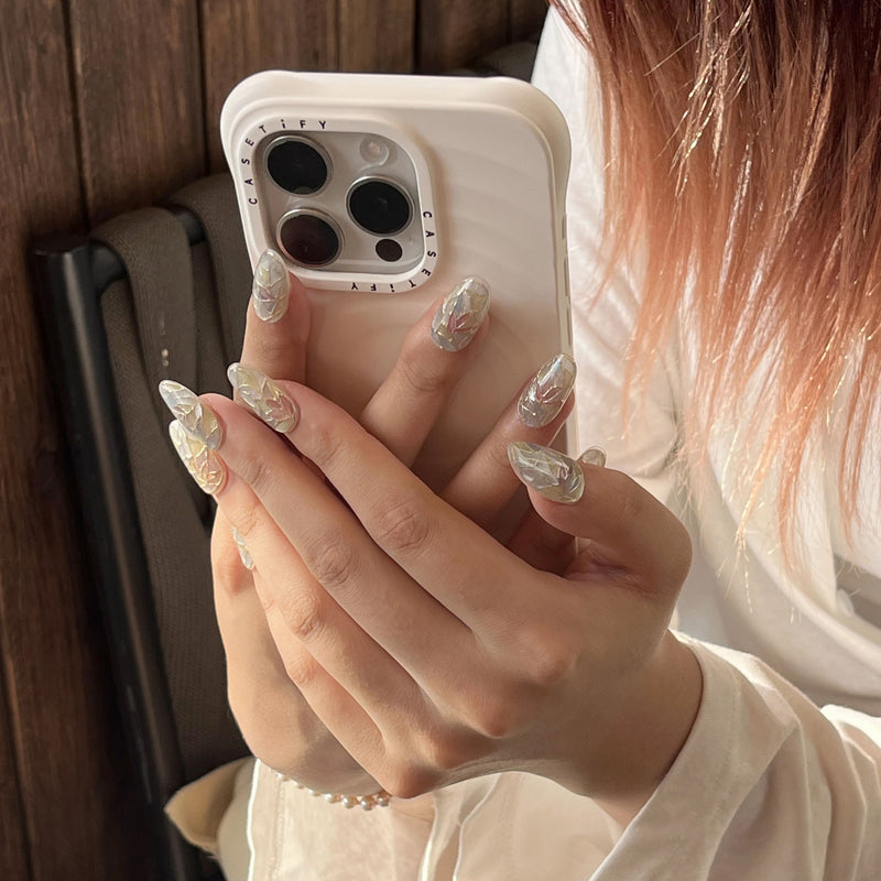 Model holding a phone while wearing Crystal Leaves silver iridescent press-on nails with mosaic leaf details