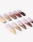 Angled flat lay of Dance of Shifting Sands press-on nails with sheer nude bases and sculpted sand to brown wave tips