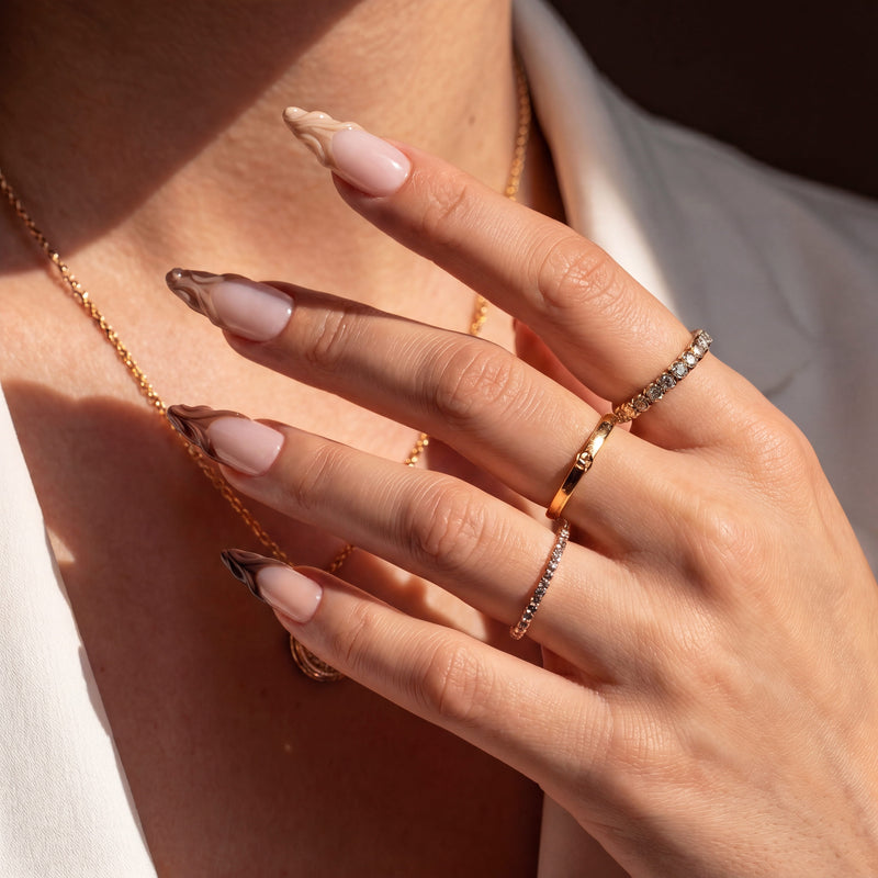 Close-up hand model wearing Dance of Shifting Sands press-on nails with glossy nude bases and sculpted brown sand wave tips in sunlight