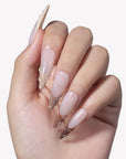 White background hand model wearing Dance of Shifting Sands press-on nails with sheer nude bases and sculpted sand brown wave tips