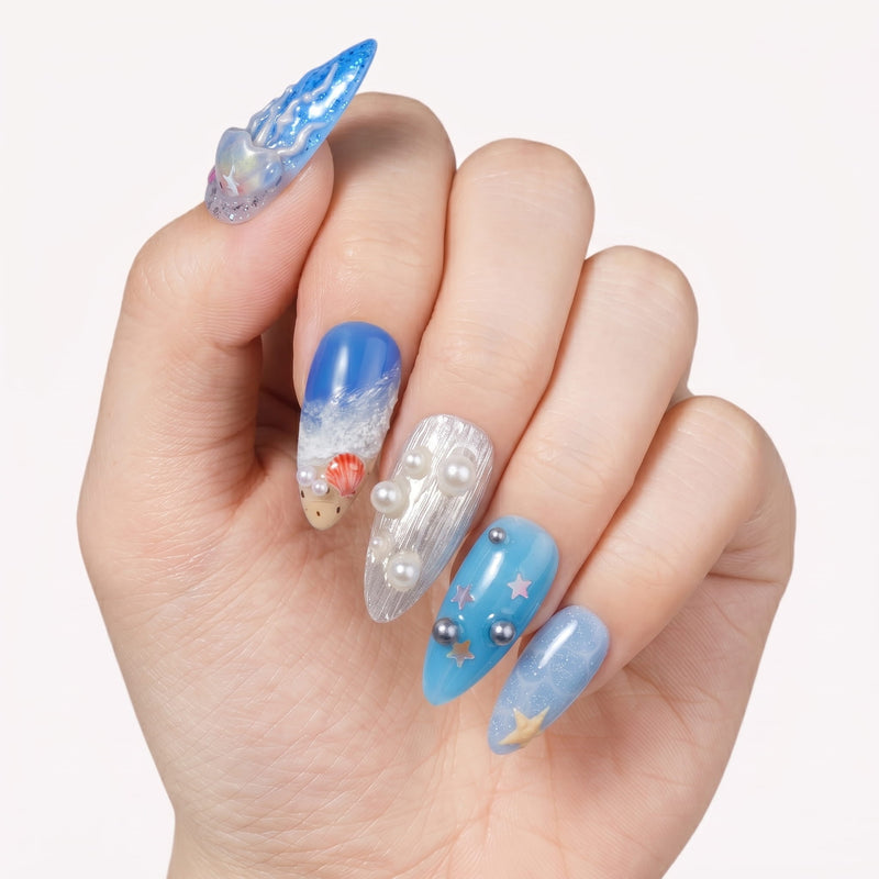 Hand model wearing Deep Sea Serenade handmade press-on nails with ocean blue waves, pearls, and starfish details.