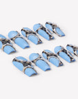 Angled flat lay of Denim Luxe press-on nails with sky blue bases, gold black leopard accents, pearl chains, and rhinestone details