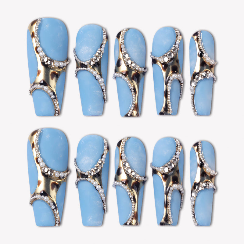 Denim Luxe press-on nails with sky blue bases, gold and black leopard accents, pearl chains, and rhinestone details