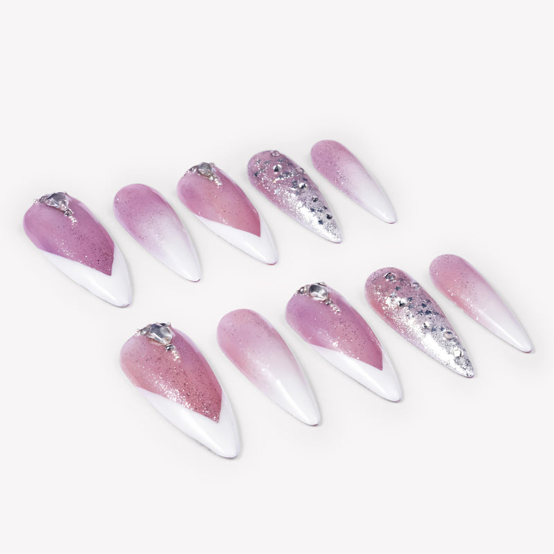 Angled flat lay of Diamond Dust pink and white stiletto press-on nails with silver glitter, rhinestones, and crystal accents