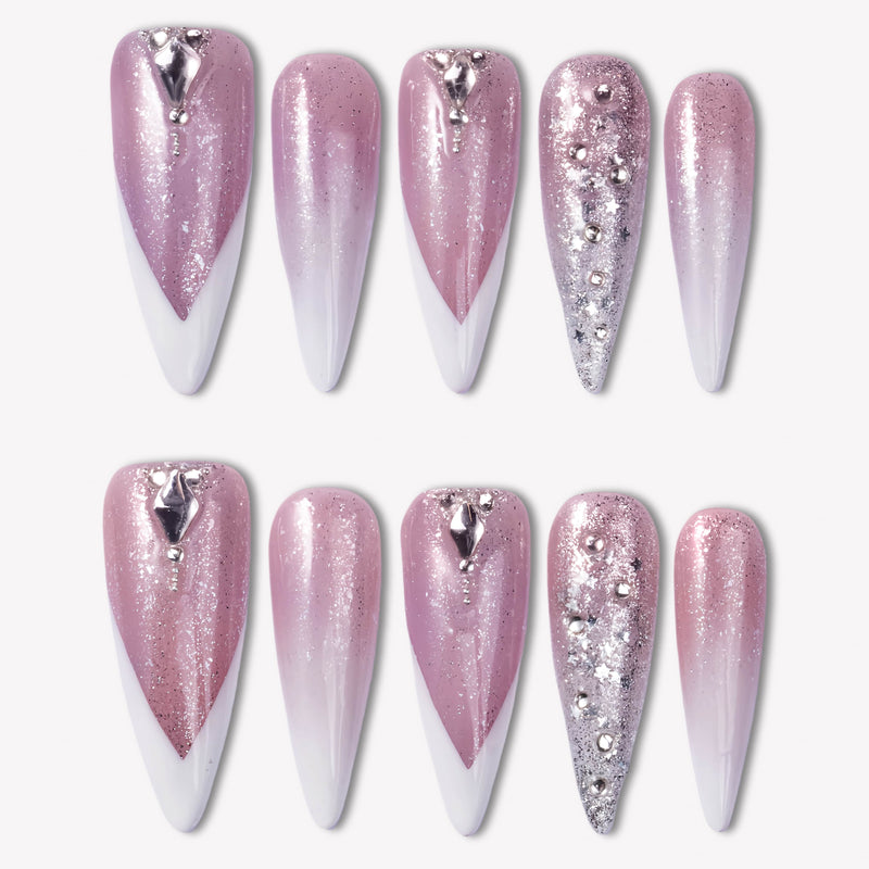Diamond Dust pink glitter press-on nails with white V French tips, silver rhinestones, and crystal charms in a flat lay