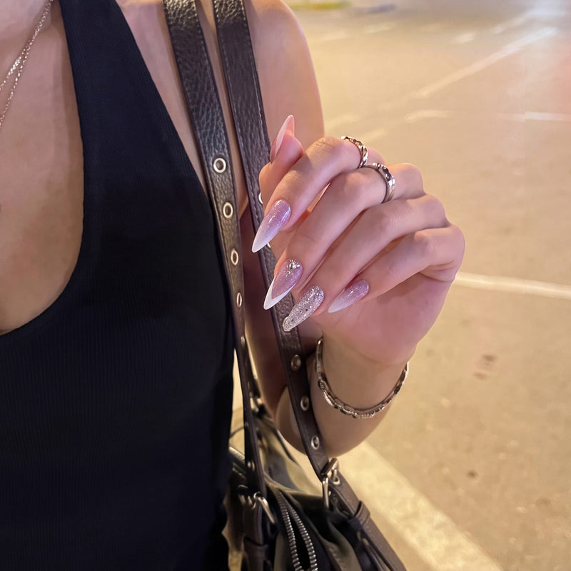 Diamond Dust pink and white glitter stiletto press-on nails shown in a street-style hand pose with silver rings