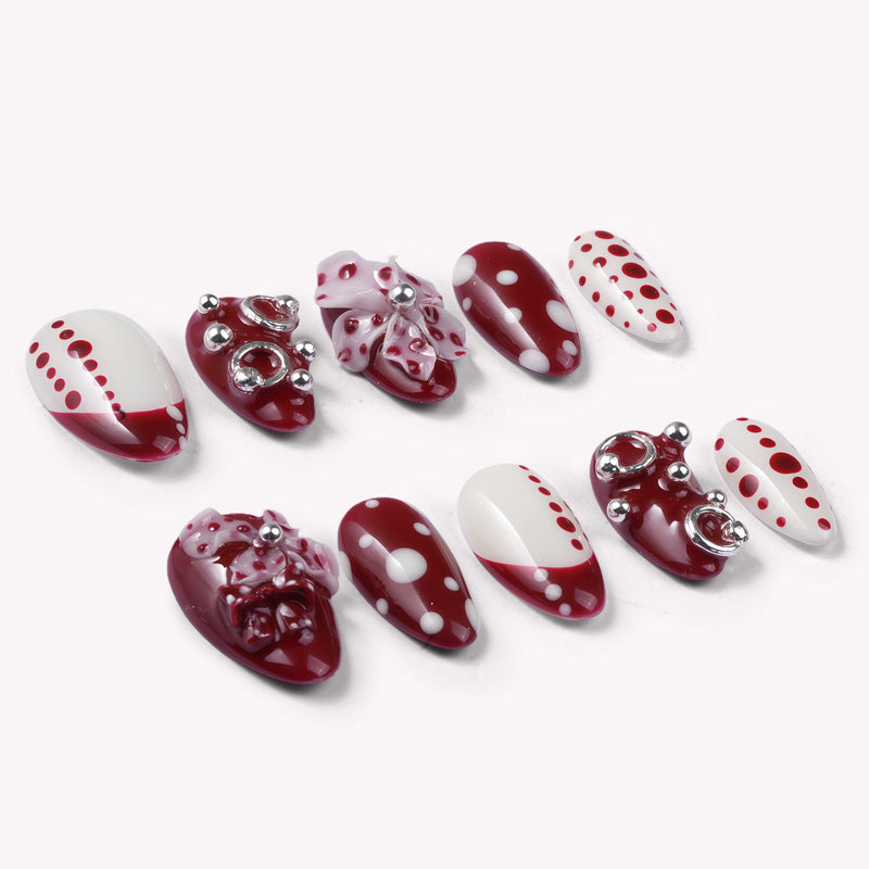 Dot Fantasy press-on nail set in red and white with polka dots and jeweled 3D accents arranged in a flat lay on a white background