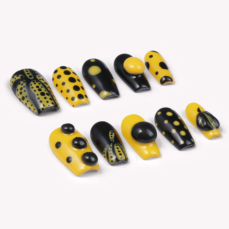 Dot Obsession press-on nails in black and yellow with bold polka dots arranged in a flat lay on a white background
