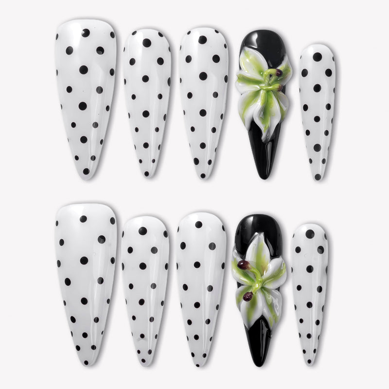 Eden Polka press-on nails with white bases, black polka dots, glossy black accent nails, and raised green white flower designs