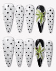 Eden Polka press-on nails with white bases, black polka dots, glossy black accent nails, and raised green white flower designs