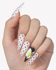 Hand model wearing Eden Polka press-on nails with white bases, black polka dots, glossy black accent nail, and raised green white flower design