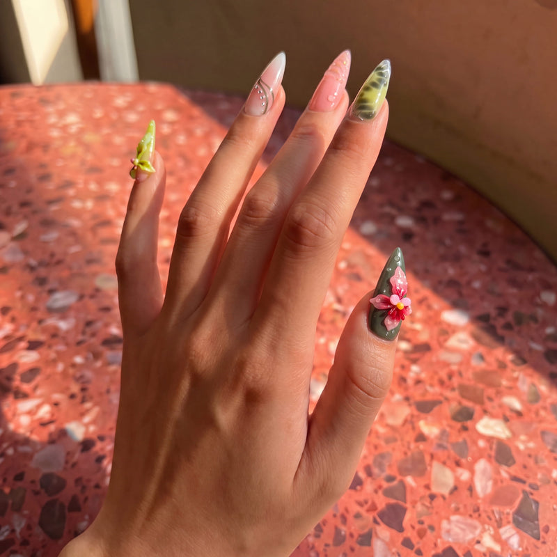 Lifestyle hand model photo of multicolor floral press-on nails in warm natural light.