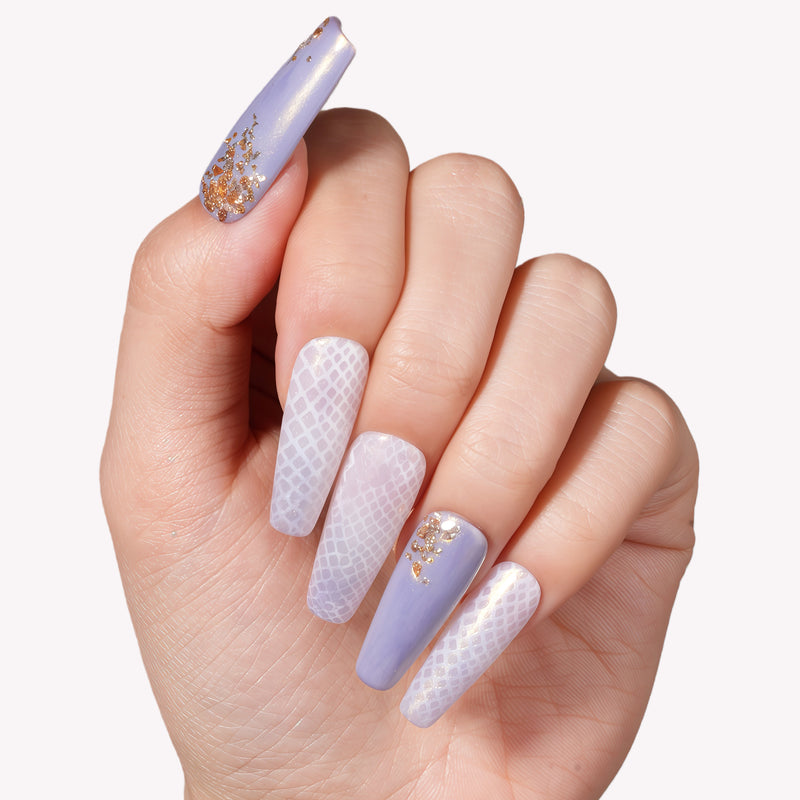 Close-up of a hand model wearing Emerald Venom press-on nails in lavender and pearl tones with gold foil accents