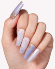 Close-up of a hand model wearing Emerald Venom press-on nails in lavender and pearl tones with gold foil accents