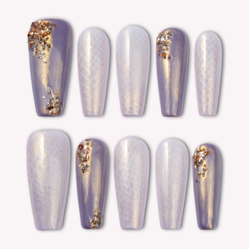 Emerald Venom press-on nails in lavender and pearl tones with gold foil accents arranged on a white background