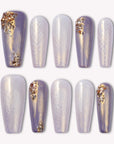 Emerald Venom press-on nails in lavender and pearl tones with gold foil accents arranged on a white background