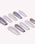 Emerald Venom press-on nails with lavender shimmer, gold foil, and snake texture arranged in a flat lay