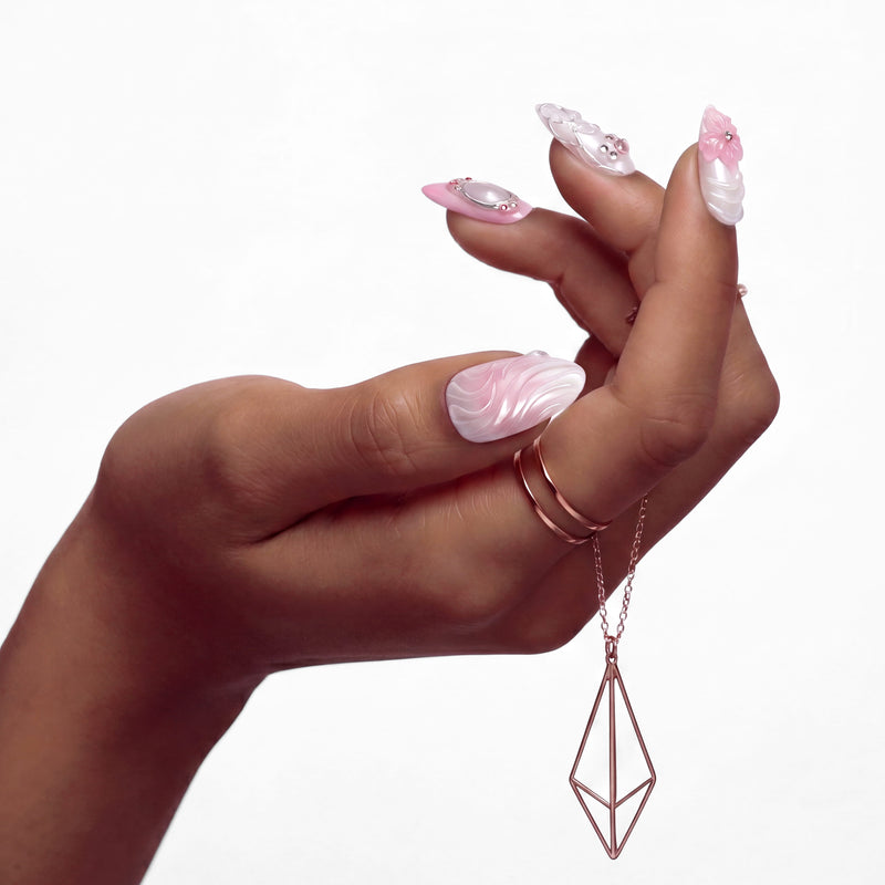 Pink ombré press-on nails with 3D floral and gem accents arranged in a flat lay