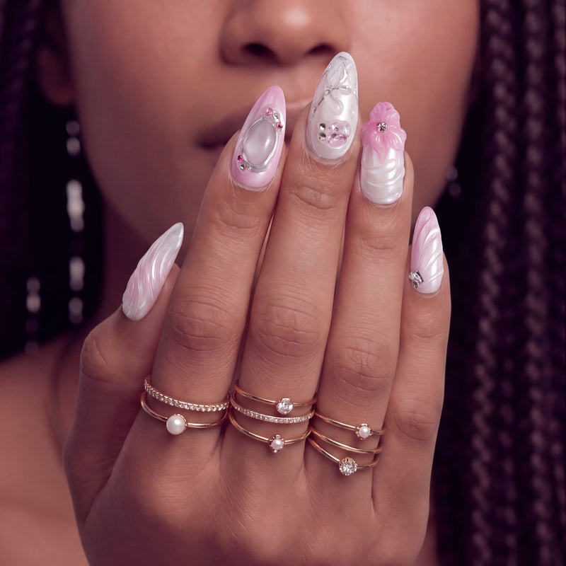 Pink ombré press-on nails with 3D floral and gem accents arranged in a set layout