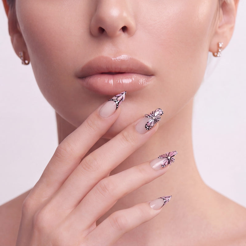 Close-up of a hand model wearing pale pink almond press-on nails with black and white butterfly accents