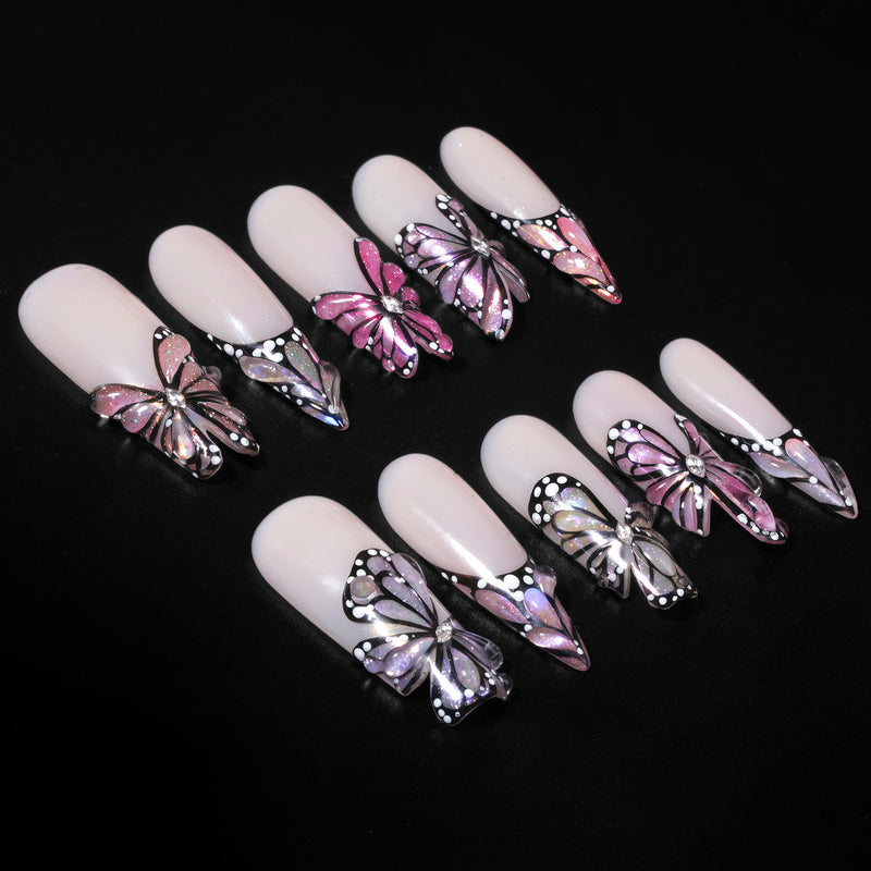 Black background flat lay of pale pink almond press-on nails with black, white, and pink butterfly accents