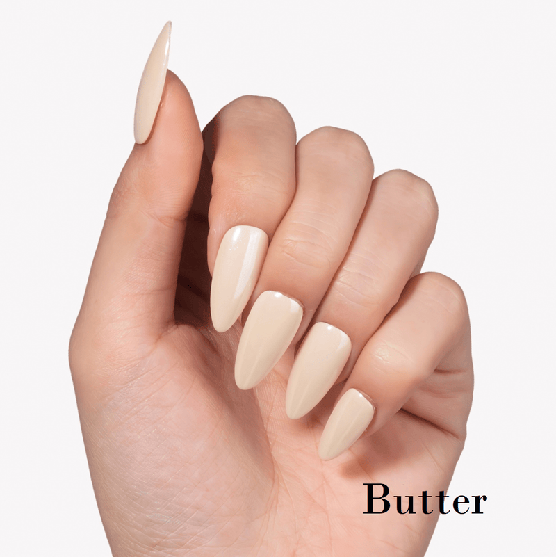 Hand model wearing Fall Essence Butter press-on nails in a creamy pale yellow shade with glossy almond-shaped tips
