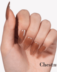 Hand model wearing Fall Essence Chestnut press-on nails in a warm chestnut brown shade with glossy almond-shaped tips