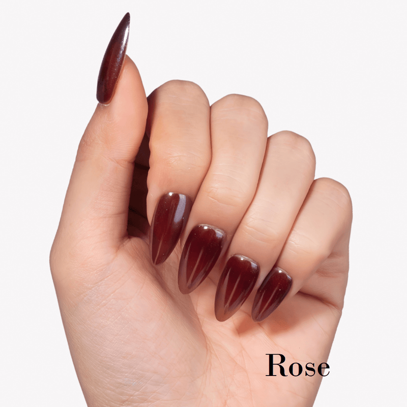 Hand model wearing Fall Essence Rose press-on nails in a deep rose red shade with glossy almond-shaped tips