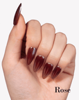 Hand model wearing Fall Essence Rose press-on nails in a deep rose red shade with glossy almond-shaped tips