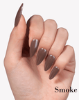 Hand model wearing Fall Essence Smoke press-on nails in a smoky gray brown shade with glossy almond-shaped tips