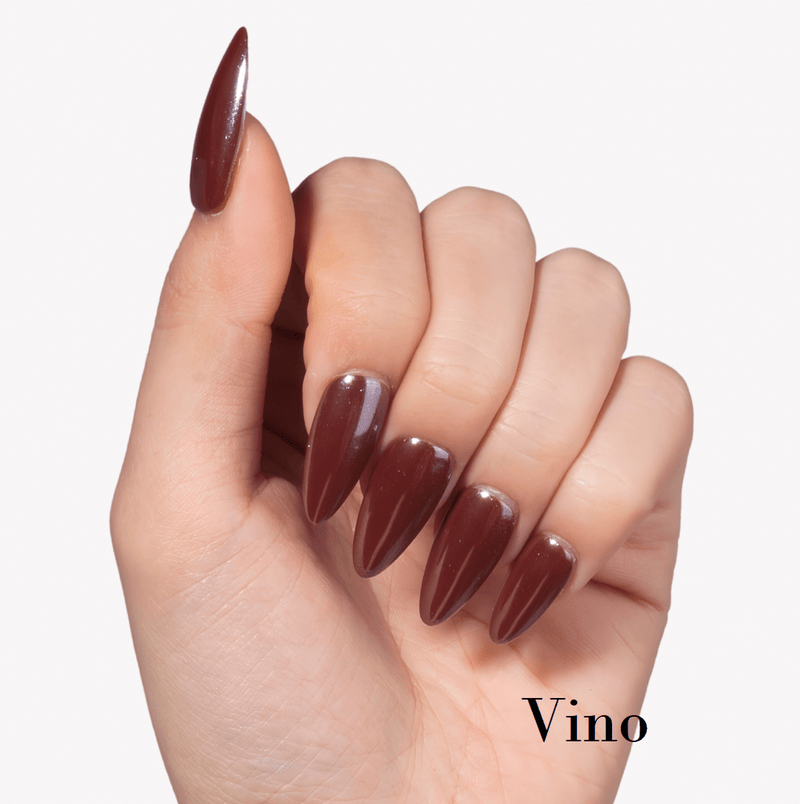 Hand model wearing Fall Essence Vino press-on nails in a deep wine red brown shade with glossy almond-shaped tips