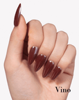 Hand model wearing Fall Essence Vino press-on nails in a deep wine red brown shade with glossy almond-shaped tips