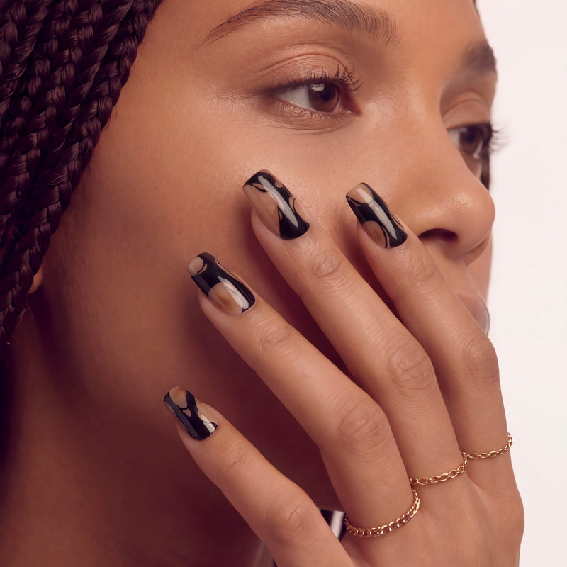 Hand model wearing Free-growing Flowers press-on nails with glossy black abstract lines and nude jelly accents